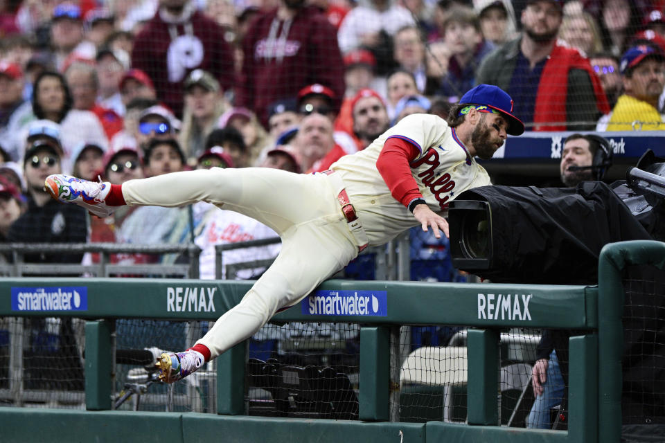 Philadelphia Phillies' Bryce Harper falls into the dugout as he gives chase for a foul ball during the first inning of a baseball game against the Atlanta Braves, Saturday, March 30, 2024, in Philadelphia. (AP Photo/Derik Hamilton)