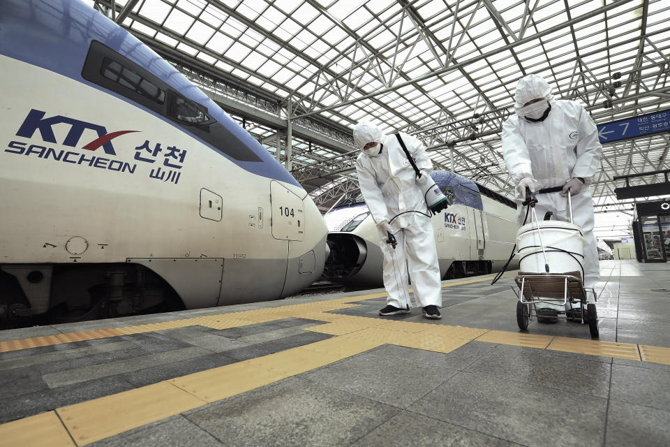 Workers wearing protective gears spray disinfectant as a precaution against the new coronavirus at Seoul Railway Station in Seoul, South Korea, Tuesday, Feb. 25, 2020. China and South Korea on Tuesday reported more cases of a new viral illness that has been concentrated in North Asia but is causing global worry as clusters grow in the Middle East and Europe. (Jin Yeon-soo/Yonhap via AP)