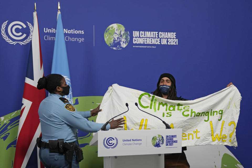 A member of security moves to apprehend a demonstrator at the COP26 U.N. Climate Summit in Glasgow, Scotland, Saturday, Nov. 13, 2021. Almost 200 nations have accepted a contentious climate compromise aimed at keeping a key global warming target alive, but it contained a last-minute change that watered down crucial language about coal. (AP Photo/Alastair Grant)