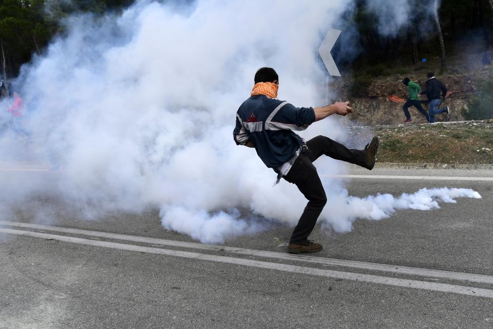 A protester kicks a tear gas canister thrown by riot police during clashes in Karava near the area where the government plans to build a new migrant detention center, on the northeastern Aegean island of Lesbos, Greece, Wednesday, Feb. 26, 2020. Local authorities declared a 24-hour strike on two eastern Greek islands Wednesday to protest government plans to build new migrant detention camps there. (AP Photo/Michael Varaklas)