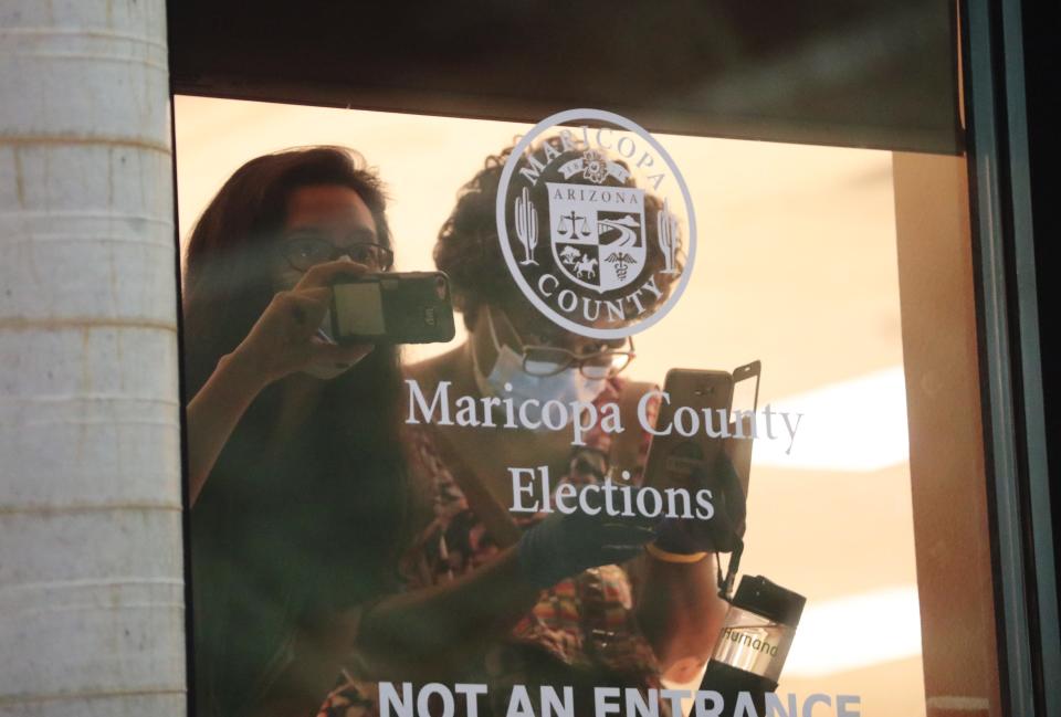 Maricopa County Election Center workers watch as supporters of President Donald Trump protest outside his office in Phoenix on Nov. 4, 2020. The group was calling for a fair vote count.