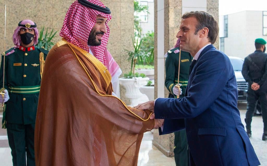 Macron greets the Crown Prince with a warm handshake upon his arrival in Saudi Arabia. - Bandar Aljaloud/Saudi Royal Palace