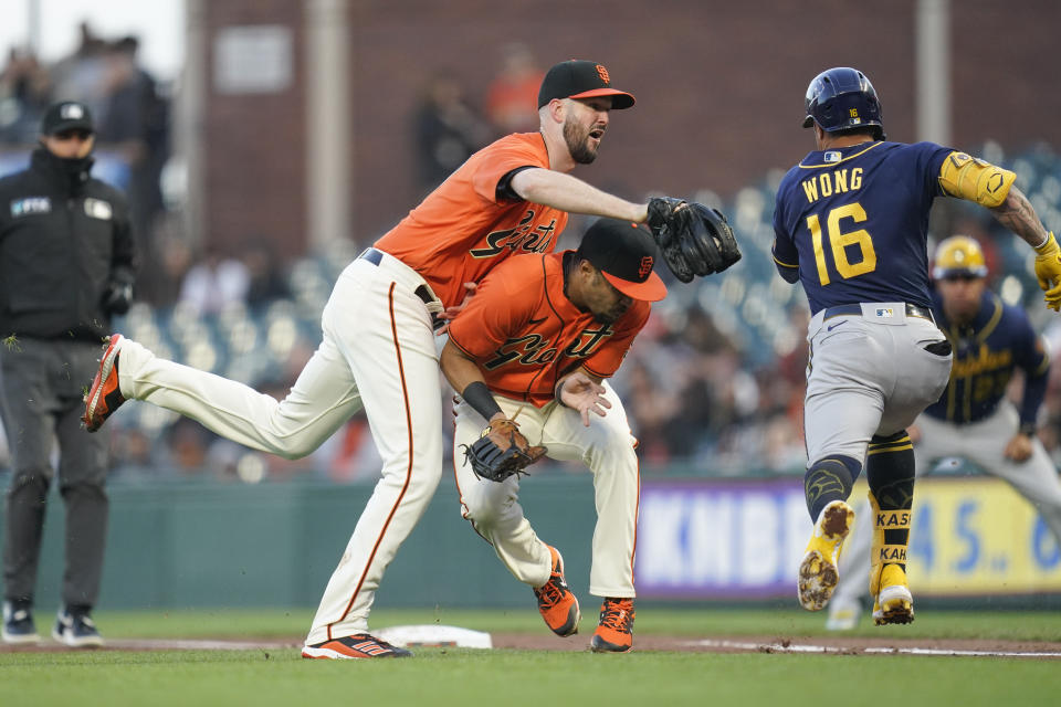 San Francisco Giants starting pitcher Alex Wood (57) runs into first baseman LaMonte Wade Jr. (31) and is unable to tag Milwaukee Brewers' Kolten Wong (16), who singled during the third inning of a baseball game in San Francisco, Friday, July 15, 2022. (AP Photo/Godofredo A. Vásquez)