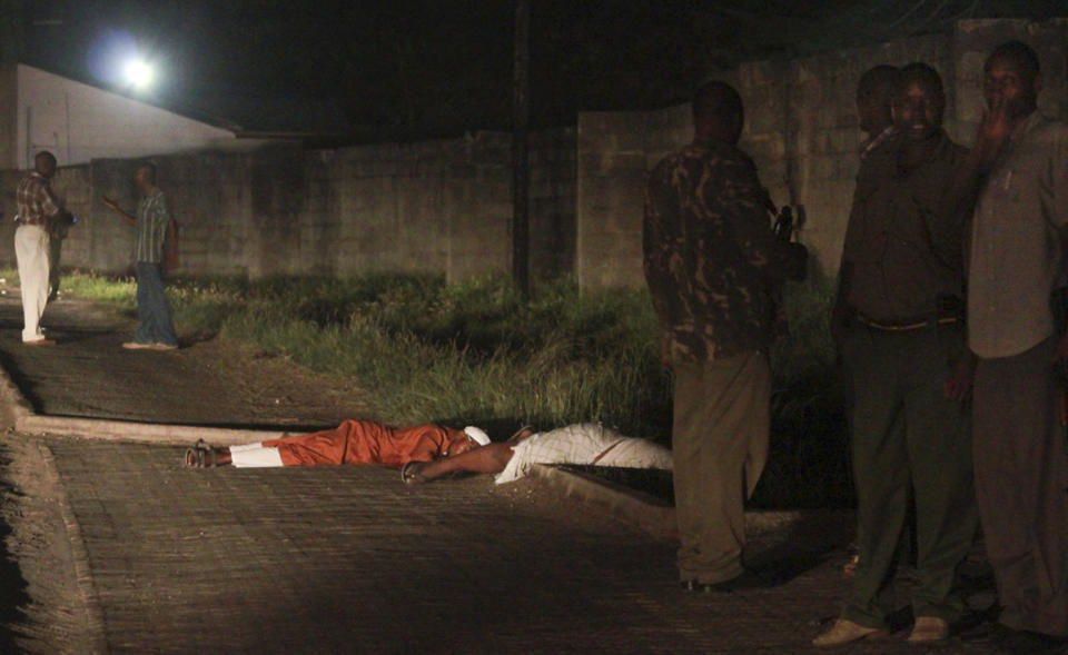 Security forces stand next to the bodies of slain muslim cleric Abubakar Shariff Ahmed, center, and another man whose identity has not yet been established, center-left, on a highway in Mombasa, Kenya Tuesday, April 1, 2014. The lawyer for radical Islamic leader Abubakar Shariff Ahmed, who had been sanctioned by the United States and the United Nations for supporting the al-Qaida-linked Somali militant group al-Shabab, says his client has been assassinated Tuesday, April 1, 2014 along with another man whose identity has not yet been established, near the Shimo la Tewa prison in Mombasa, Kenya. (AP Photo)