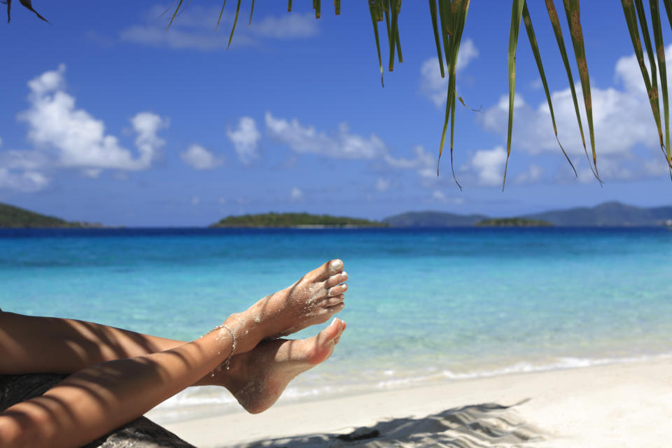 woman with sandy feet relaxing on a tropical beach in the Caribbean