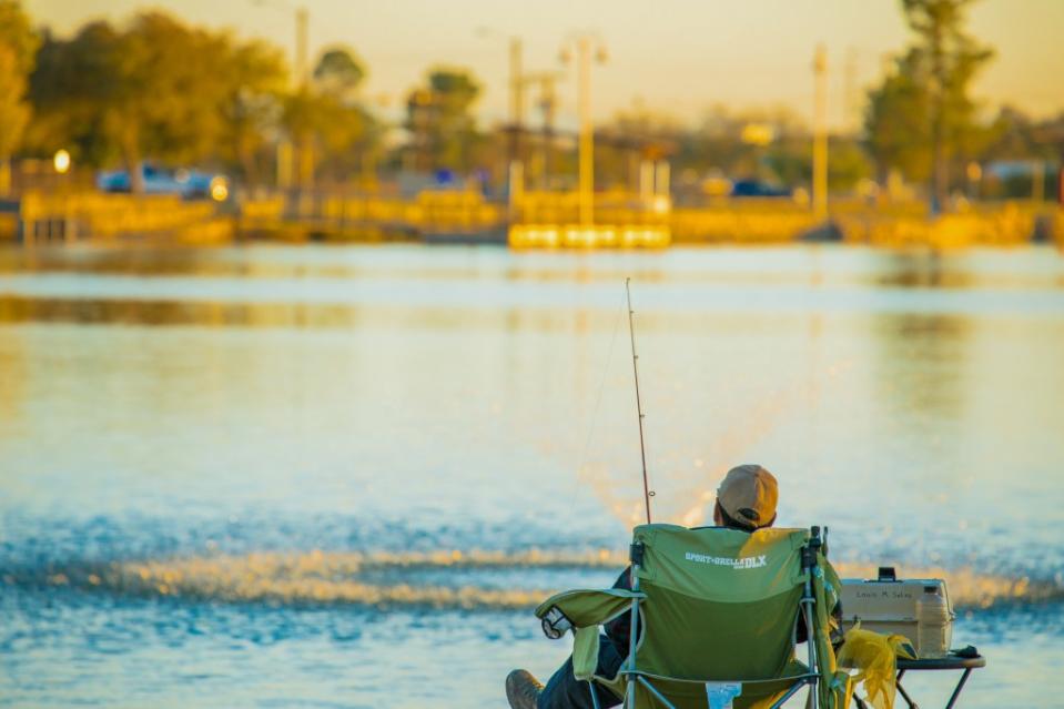 A man sitting on his fishing chair fishing and enjoying the tranquil view of Ascarate Park Via Getty Images