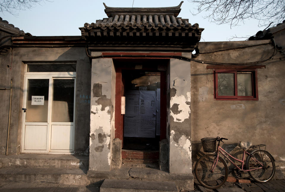 In this photo taken on Dec. 26, 2012, a bicycle is parked outside a Hutong home with a demolition notice seen behind the entrance wall near the historical Drum and Bell Tower in Beijing. The district government wants to demolish these dwellings, move their occupants to bigger apartments farther from the city center and redevelop a square in 18th century Qing Dynasty fashion. (AP Photo/Andy Wong)