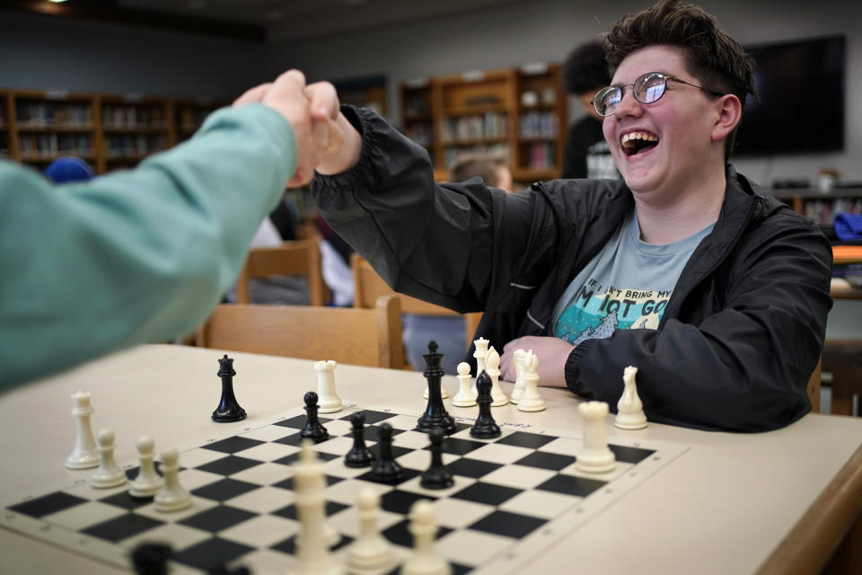 Reeds Brook Middle School chess team member Lucien Paradis shakes hands after defeating his opponent during an after-school chess practice, Tuesday, April 25, 2023, in Hampden, Maine. Part-time chess coach and full-time custodian David Bishop led his elementary and middle school teams to state championship titles this year. (AP Photo/Robert F. Bukaty)