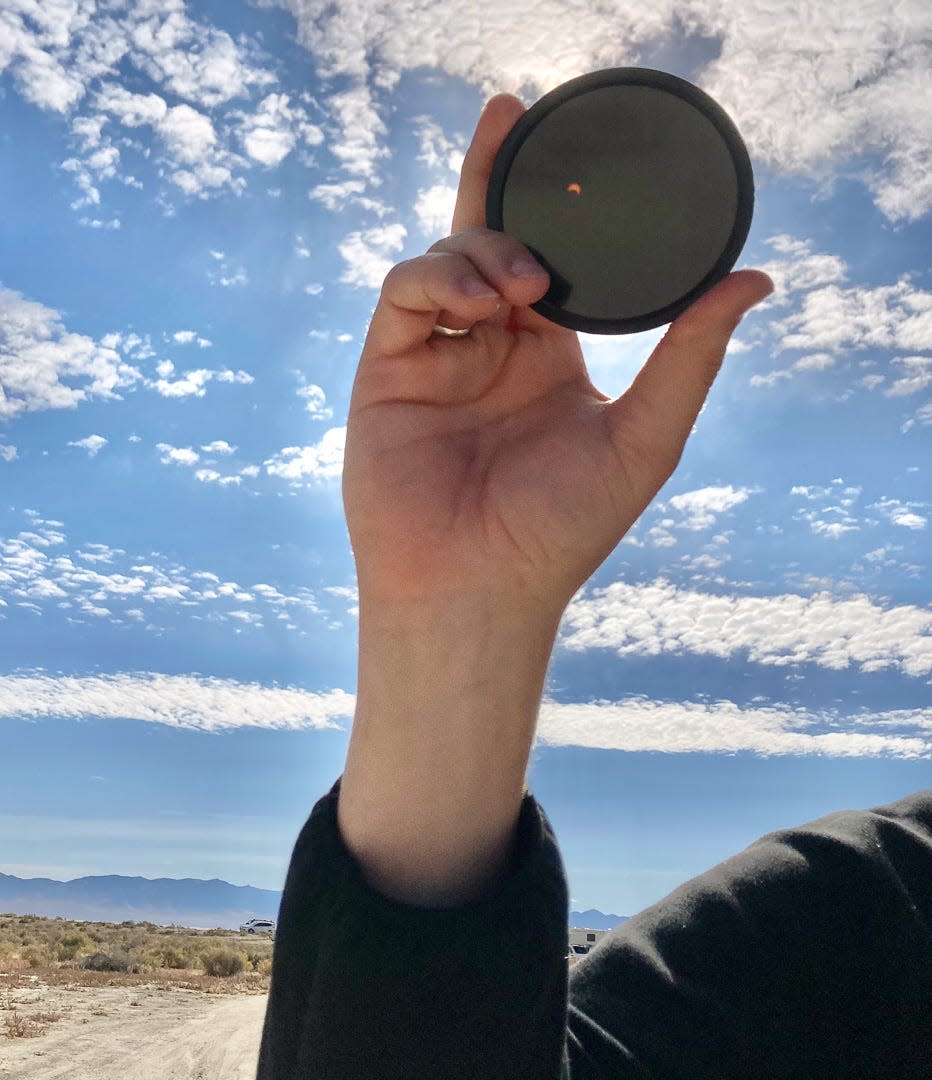 Photographer Carly Stocks holds a solar filter showing the partial eclipse on Oct. 14, 2023 at Sevier Lake in Utah.