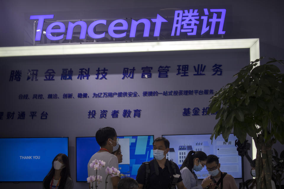 In this Sept. 5, 2020 photo, people look at a display from Chinese technology firm Tencent at the China International Fair for Trade in Services (CIFTIS) in Beijing. China's internet watchdog has fined technology platforms operated by e-commerce company Alibaba and gaming firm Tencent for spreading sexually suggestive content involving children, as regulators sought to clean up the internet of content harmful to minors. (AP Photo/Mark Schiefelbein)