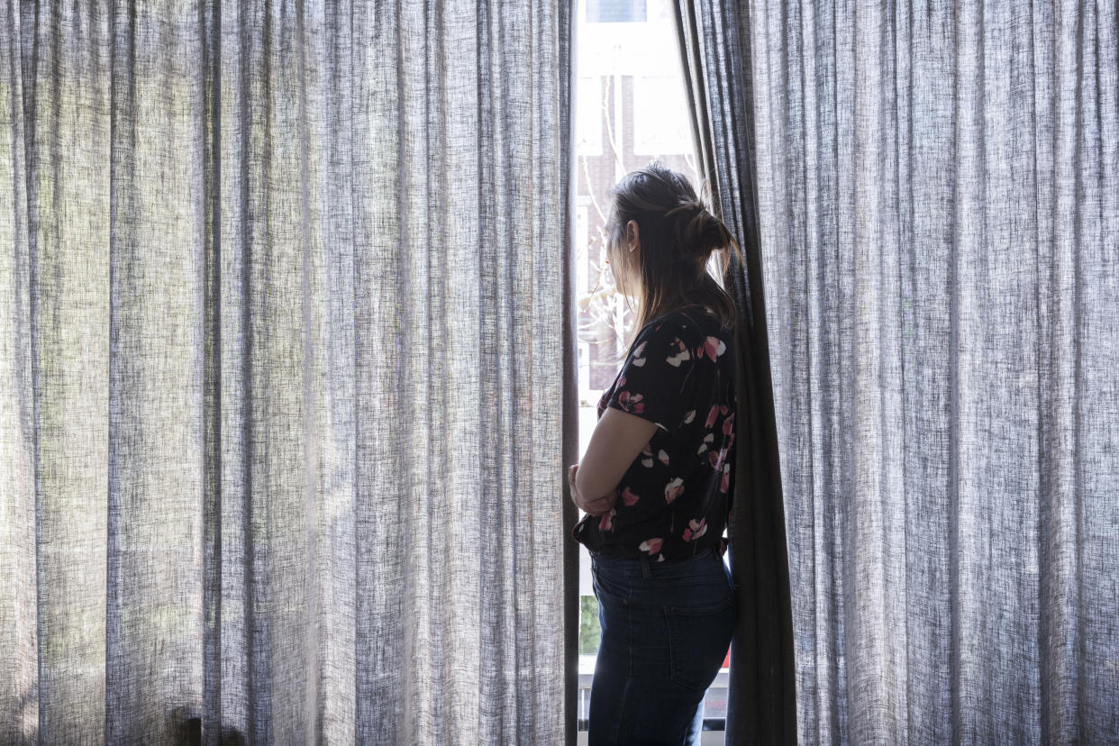 Woman looking outside the window during quarantaine.