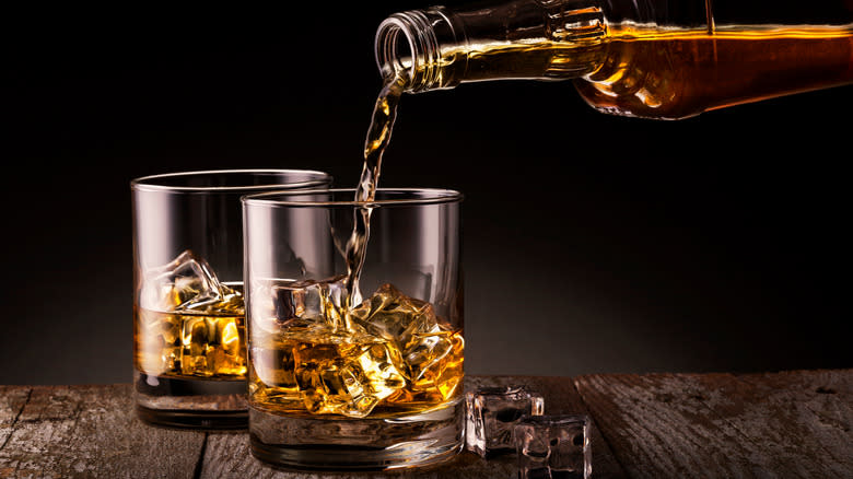 Bourbon being poured from a bottle into two glasses