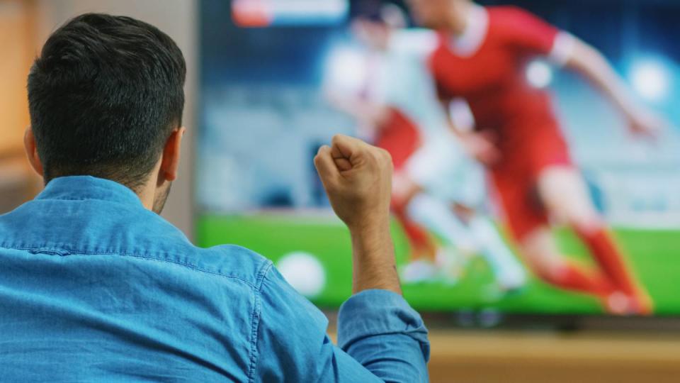 Un homme regarde du football à la télévision