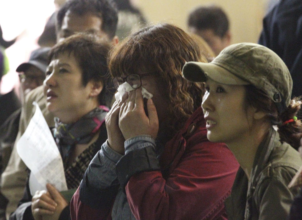 A mother weeps as she and others search for their children's names among a list of survivors rescued from a ferry that sank off the country's southern coast, at Danwon high school in Ansan, South Korea, Wednesday, April 16, 2014. Dozens of boats, helicopters and divers scrambled to rescue more than 470 people, including 325 students on a school trip from the high school, after the ship sank earlier in the day. (AP Photo/Ahn Young-joon)