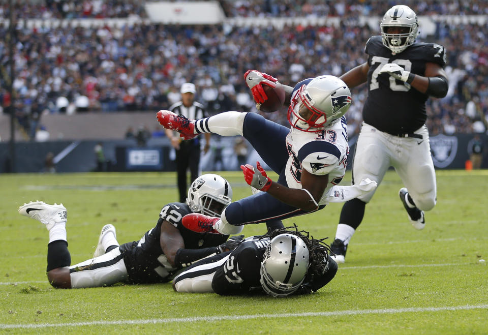 <p>New England Patriots Dion Lewis, center, scores a touchdown against Oakland Raiders Karl Joseph, bottom left, and Reggie Nelson, bottom right, during the first half of their 2017 NFL Mexico Game at the Estadio Azteca in Mexico City, Nov. 19, 2017. (Photo by Jessica Rinaldi/The Boston Globe via Getty Images) </p>