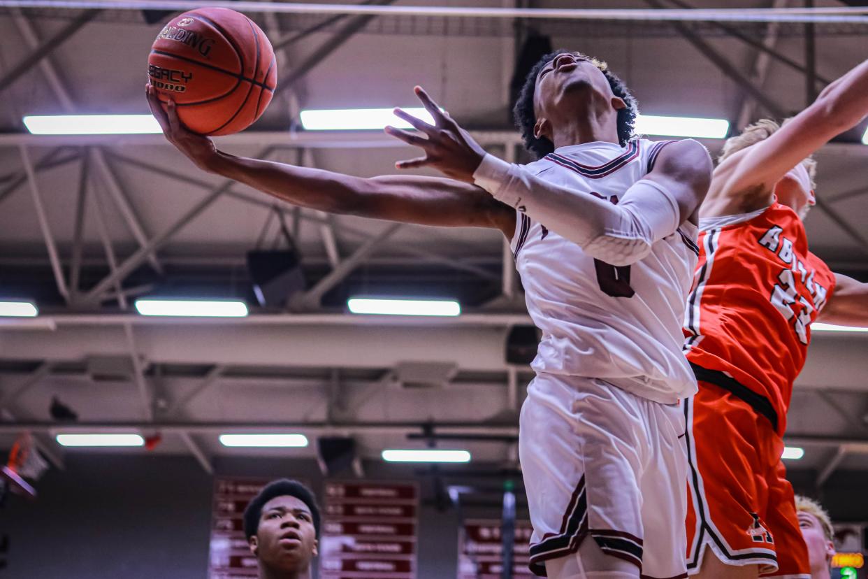 Salina Central’s Sid Duplessis IV (0) puts up a one handed layup while being guarded by Abilene’s Cooper Wildey (23) in Thursday’s game at Central gym.