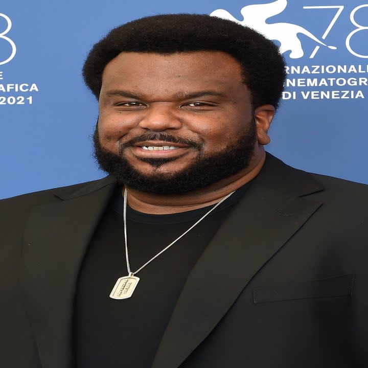 Craig Robinson in a suit smiling at the camera