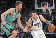 Dallas Mavericks' Luka Doncic (77) drives against San Antonio Spurs' Jakob Poeltl during the first half of an NBA basketball game Saturday, Dec. 31, 2022, in San Antonio. (AP Photo/Darren Abate)