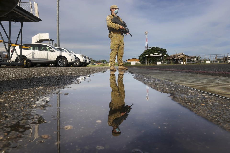 An Australian soldier stands on the tarmac at Honiara Airport, Solomon Islands, Tuesday, Nov. 30, 2021. New Zealand announced Wednesday, Dec. 1, 2021, that they will send up to 65 military and police personnel to the Solomon Islands over the coming days after rioting and looting broke out there last week.(Gary Ramage via AP)