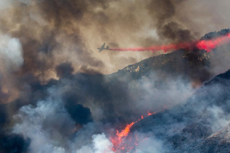 In this Saturday, Sept. 5, 2020, file photo, an air tanker drops fire retardant on a hillside wildfire in Yucaipa, Calif. A hotter world is getting closer to passing a temperature limit set by global leaders five years ago and may exceed it in the next decade or so, according to a new United Nations report released on Wednesday, Sept. 9, 2020.