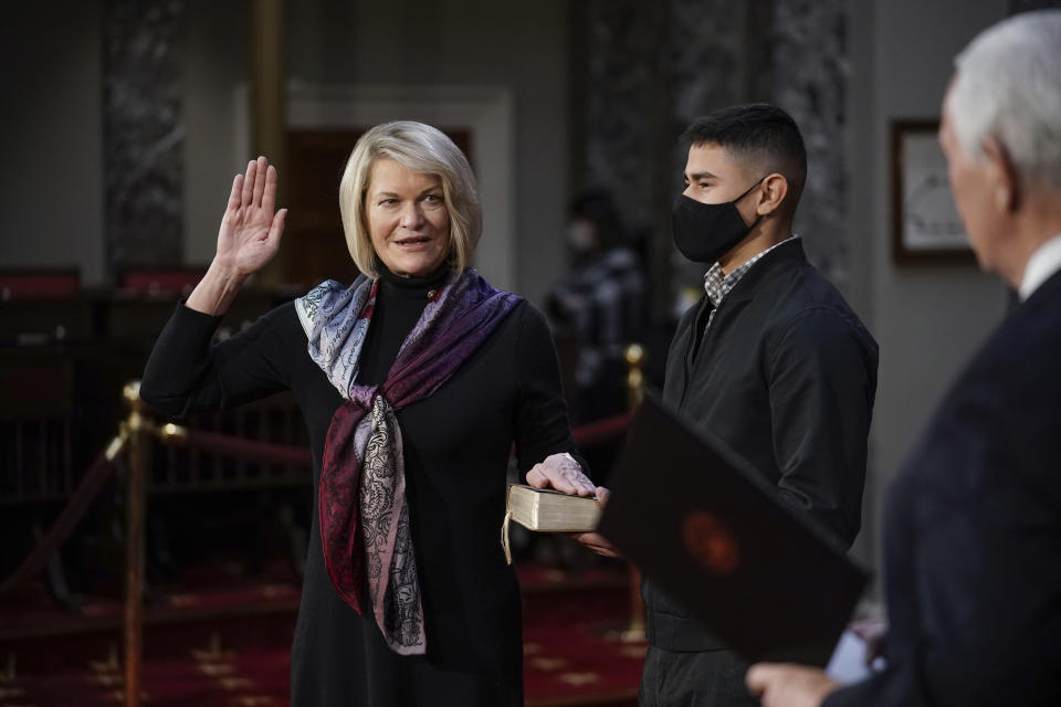 FILE - In this Jan. 3, 2021, file photo, Sen. Cynthia Lummis, R-Wyo., is joined by her nephew Alexandro Giovanni Lozano, as she takes the oath of office from Vice President Mike Pence during a reenactment ceremony in the Old Senate Chamber at the Capitol in Washington. A deepening divide among Republicans over President Donald Trump's efforts to overturn the election runs prominently through Wyoming, the state that delivered Trump's widest prevailing margin by far. Eleven Republican senators saying they will not be voting Wednesday, Jan. 6, 2021 to confirm President-elect Joe Biden's victory include Wyoming's newly sworn in Sen. Lummis, a Cheyenne-area rancher and former congresswoman. (AP Photo/J. Scott Applewhite, Pool, File)