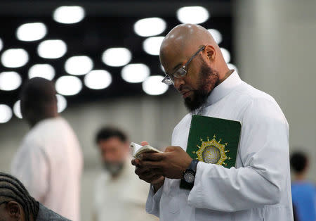 Sayfullaah Ali reads from a prayer book before taking part at the jenazah, an Islamic funeral prayer, for the late Muhammad Ali at Freedom Hall in Louisville, Kentucky, June 9, 2016. REUTERS/John Sommers II