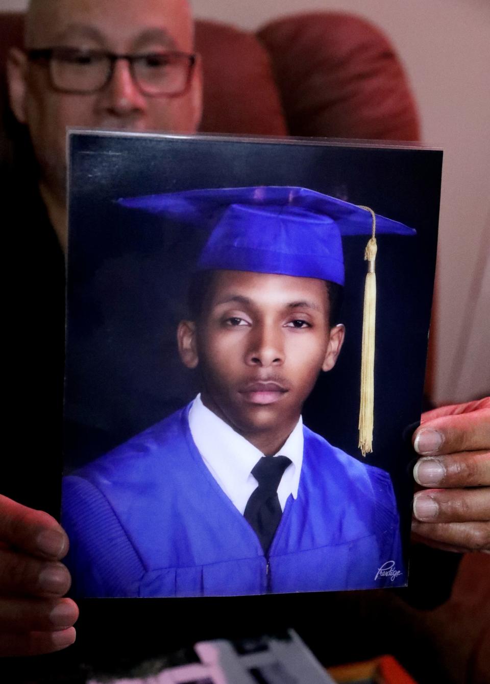 The step-father Antonio Thompson, who was close to Christopher Jones-McClean, holds up a graduation photo of Christopher Jones-McClean who was killed in the garage of his home in Murfreesboro, on Oct. 12, 2023. The family of Jones-McClean are asking the community for tips to solving the death of their loved one.
