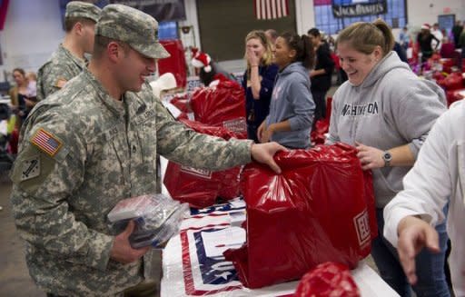 Staff Sergeant Shane Uras (L) picks up donated Christmas gifts for his family from USO volunteer Lyndsay Gorton (R) at Fort Belvoir, Virginia. The USO found donors to provide gifts for a record 1,600 children this Christmas