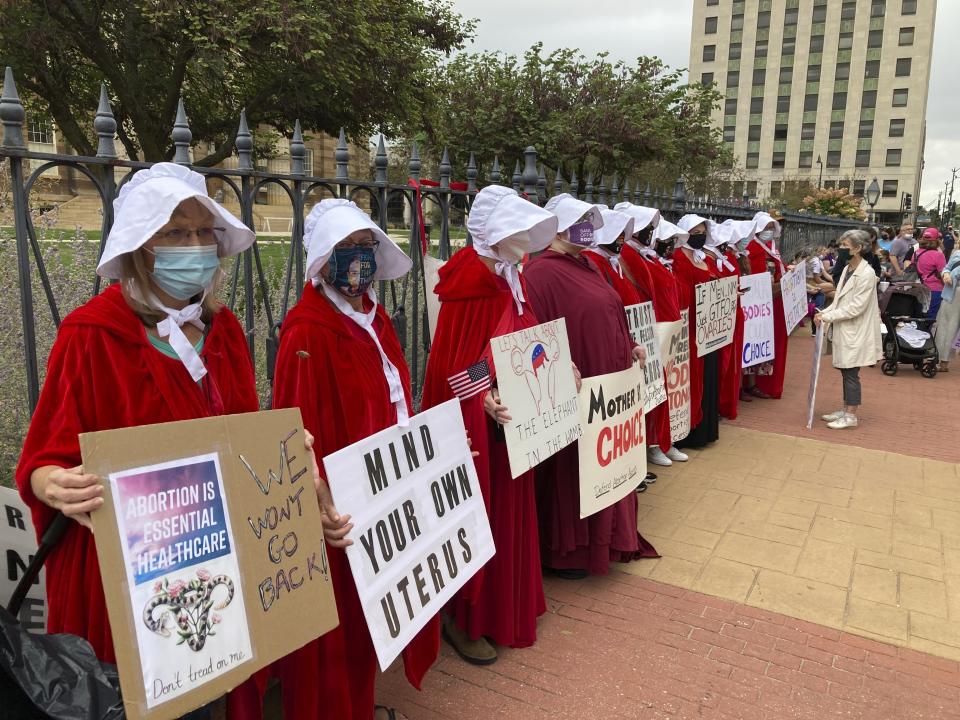 FILE - In this Oct. 22, 2021 file photo, Illinois Handmaids protest abortion restrictions at a rally in downtown Springfield, Ill. Rep. Anna Moeller, D-Elgin, is sponsoring legislation to repeal a law requiring that their parents or guardians of minors seeking abortions be notified at least 48 hours in advance. An expected decision by the U.S. Supreme Court in the coming year to severely restrict abortion rights or overturn Roe v. Wade entirely is setting off a renewed round of abortion battles in state legislatures. (AP Photo/John O'Connor File)