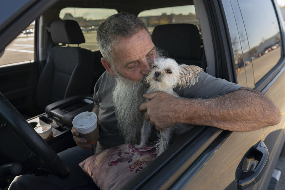 Joe Smith kisses his dog Presley as he drinks a cup of White Castle coffee in his truck after work in Columbus, Ohio, Tuesday, Oct. 24, 2023. Smith did not picture raising his granddaughter, but when his daughter's substance use disorder meant she couldn't care for her child, that's where Smith and his wife found themselves nineteen years ago. (AP Photo/Carolyn Kaster)