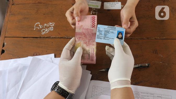 Petugas menyerahkan bantuan sosial (bansos) dari Pemerintah Provinsi Banten kepada warga di Pinang, Tangerang, Jumat (1/5/2020). Bansos berupa uang tunai sebesar Rp 600 ribu tersebut diberikan kepada warga yang terdampak virus corona COVID-19. (Liputan6.com/Angga Yuniar)