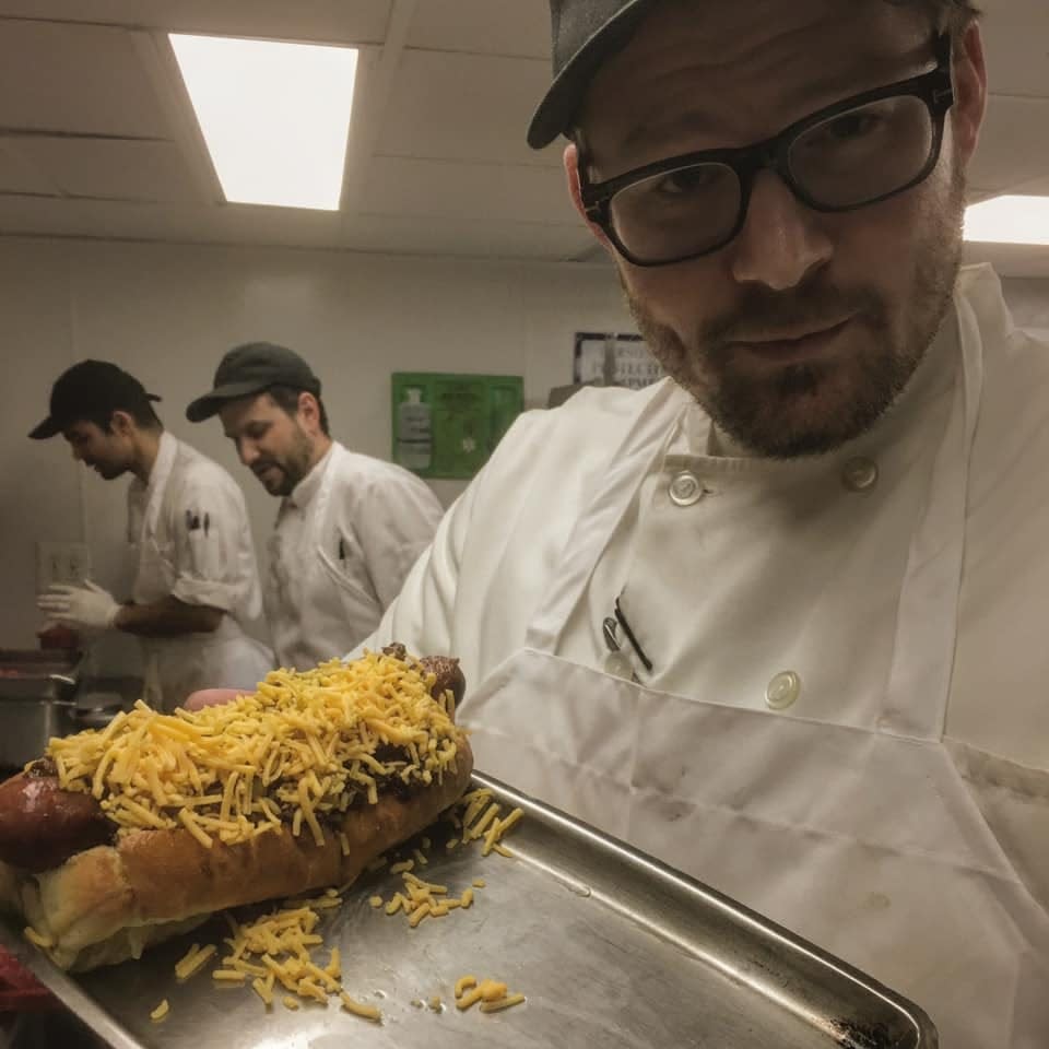 Chef Travis Reidel poses with an elevated Cincinnati-style cheese coney (before the cheese melted) at Gramercy Tavern, in New York City.