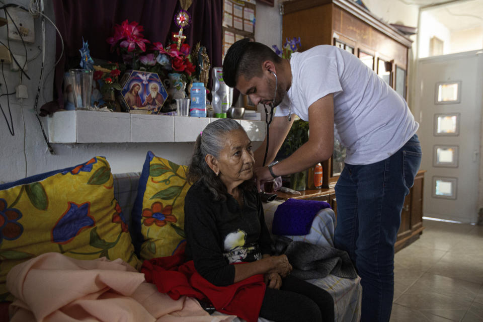 El doctor Juan Antonio Salas escucha los pulmones de la sobreviviente de COVID-19 Cleotilde Borja durante una visita de seguimiento en su casa en la Ciudad de México, el viernes 5 de junio de 2020. (AP Foto/Fernando Llano)