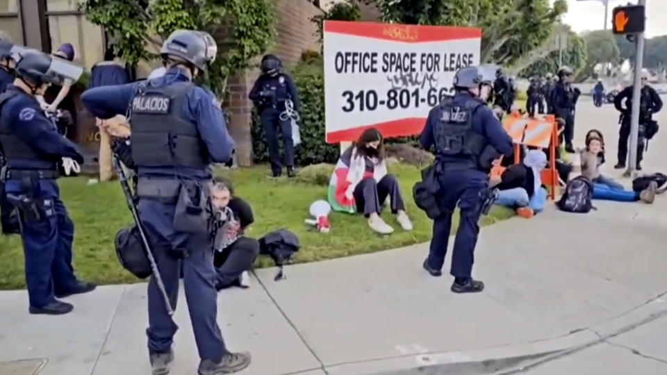 This video still image provided by KABC-TV shows protesters being detained prior to being arrested by Los Angeles police officers on Wednesday, Dec. 27, 2023, near Los Angeles International Airport. Pro-Palestinian protesters briefly blocked entrance roads to airports in New York and Los Angeles on Wednesday, forcing some travelers to set off on foot to bypass the jammed roadway. (KABC-TV via AP)