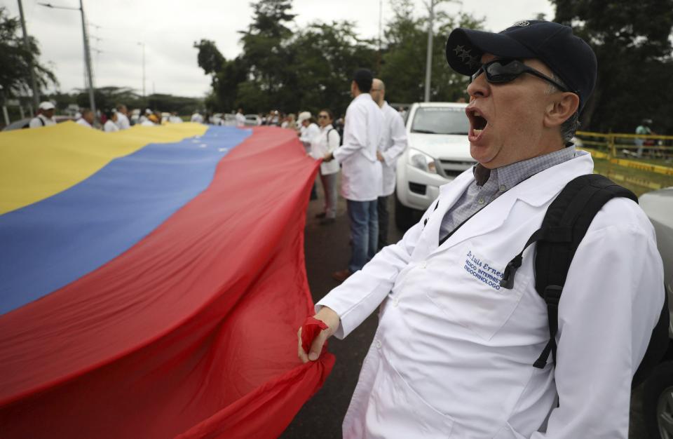 Venezuelan doctors shout slogans against the government of Venezuela's President Nicolas Maduro at the International Bridge Tienditas, which has been blocked by the Venezuelan military, near Cucuta, Colombia, Sunday, Feb. 10, 2019, across the border from Tachira, Venezuela. The doctors, who crossed into Colombia for the protest, are demanding their nation’s military allow humanitarian aid into the country, while Venezuelan President Nicolas Maduro contends the aid delivery is part of a larger U.S. intervention to remove him from power. (AP Photo/Fernando Vergara)