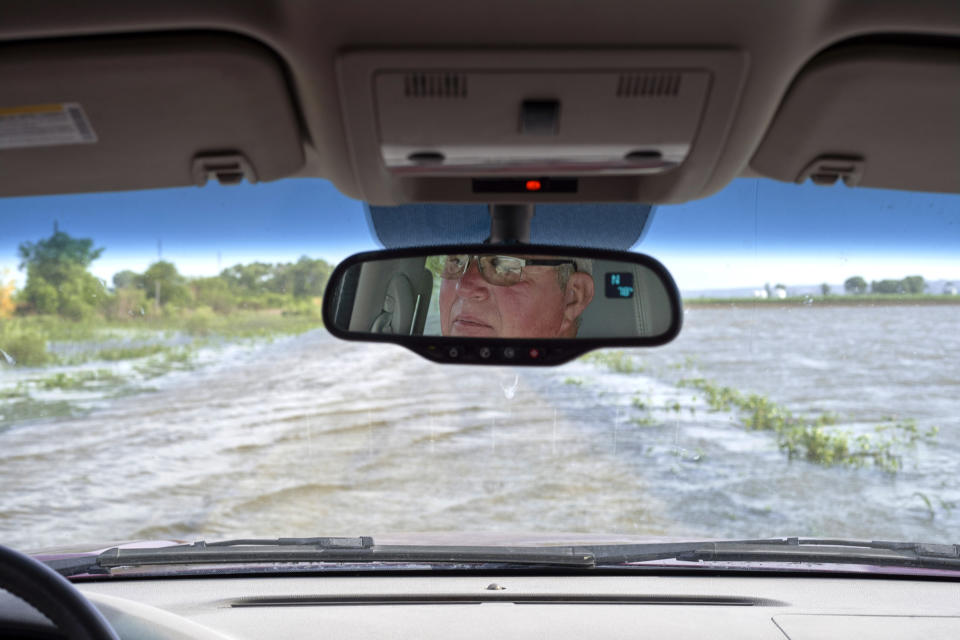 In this June 27, 2019 photo, Gene Walter, of Crescent, Iowa, drives his truck through a flooded road that sits between flooded fields in Crescent, Iowa. This year's record rainfall and devastating flooding are forcing tough decisions about the future of farming in in the face of climate change. Like many in the water-weary Midwest, Walter doesn't know if climate change was responsible for the second major flood in nine years. Or the increasingly frequent torrential rains that dump more water in an hour than he used to see in days. (AP Photo/Nati Harnik)
