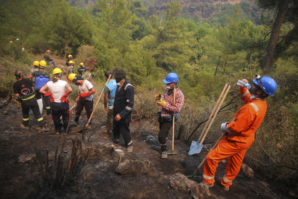 Turkish volunteers work as they fight wildfires in Turgut village, near tourist resort of Marmaris, Mugla, Turkey, Wednesday, Aug. 4, 2021. Hundreds of volunteers have joined efforts to contain blazes that have swept through forests in Turkey's southern and southwestern coasts, fueled by a summer heatwave, low humidity and strong winds. The fires, described as Turkey's worst in living memory, have so far killed eight people _ including a teenaged volunteer who was carrying drinking water and other refreshments to firefighters in Marmaris. (AP Photo/Emre Tazegul)