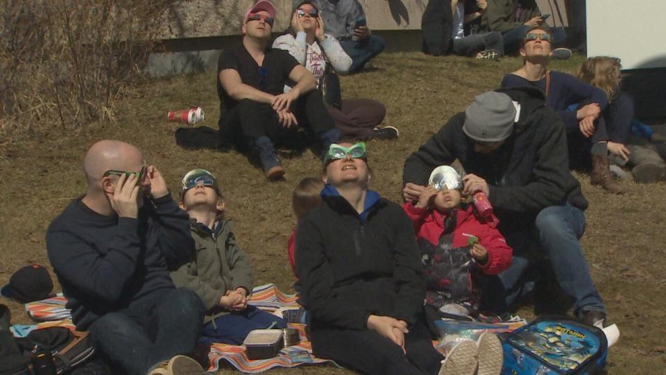 Crowds found patches of grass to sit and watch the solar eclipse at the University of Calgary campus. 