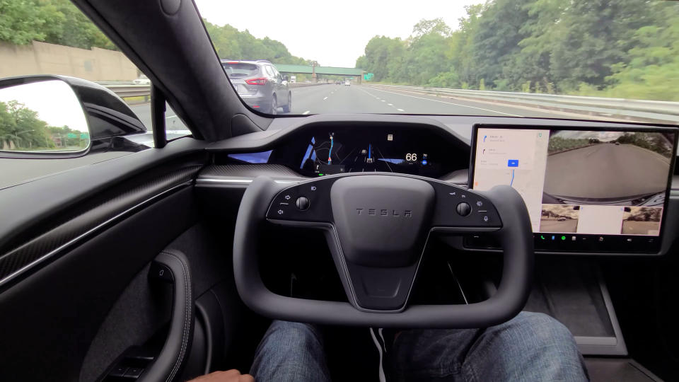 Missouri, United States - March 14, 2022: Close-up of a Tesla Model S plaid, driving down a highway on autopilot. And a man sitting with his hands on his legs.