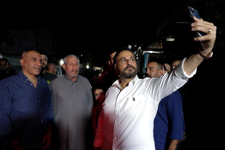 Imad Al-hamdani, right, a candidate for the parliamentary elections, takes a picture with the people in a market in Baghdad, Iraq, Monday, Oct. 27, 2021. The candidates know convincing Iraq's disillusioned youth to trust in an electoral process tainted with a history of tampering and fraud is their best chance to win seats. (AP Photo/Hadi Mizban)