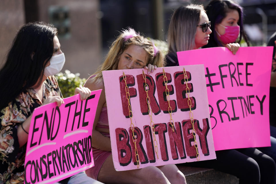 Alandria Brown, second from left, of Hendersonville, Tenn., sits with William Henry of Los Angeles, far left, and other Britney Spears supporters outside a court hearing concerning the pop singer's conservatorship at the Stanley Mosk Courhouse, Thursday, Feb. 11, 2021, in Los Angeles. (AP Photo/Chris Pizzello)