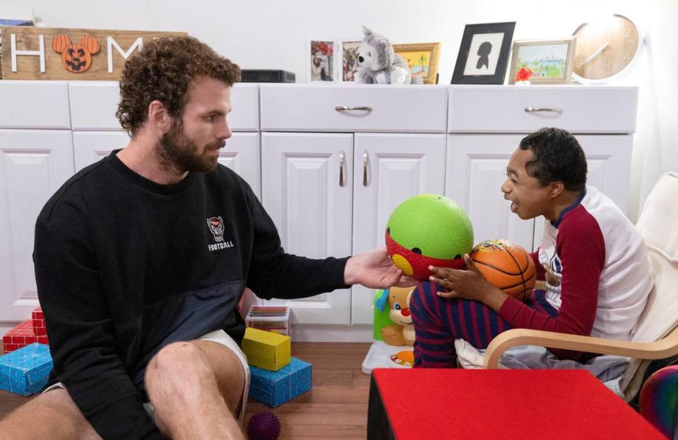 Grayson Ketchie plays ball with N.C. State linebacker Payton Wilson at Grayson’s home in Garner Wednesday, Oct. 18, 2023. Ketchie, 12, has been suffering from severe neurological issues since he was a baby. He has been a Wolfpack fan since he was three and the players made a surprise visit to his home that evening.