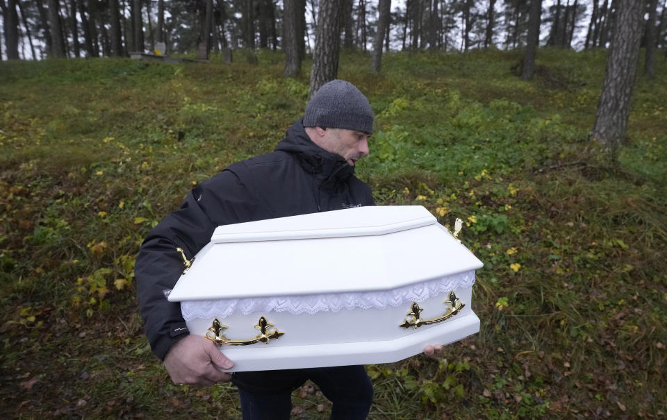 A man lowers into a grave a tiny white casket of an unborn Iraqi boy, in Bohoniki, Poland, on Tuesday Nov. 23, 2021. The child is the latest life claimed as thousands of migrants from the Middle East have sought to enter the European Union but found their path cut off by a military build-up and fast approaching winter in the forests of Poland and Belarus. (AP Photo/Czarek Sokolowski)
