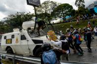 Venezuelan opposition activists confront a police armoured vehicle during a protest against President Nicolas Maduro, in Caracas, on May 1, 2017