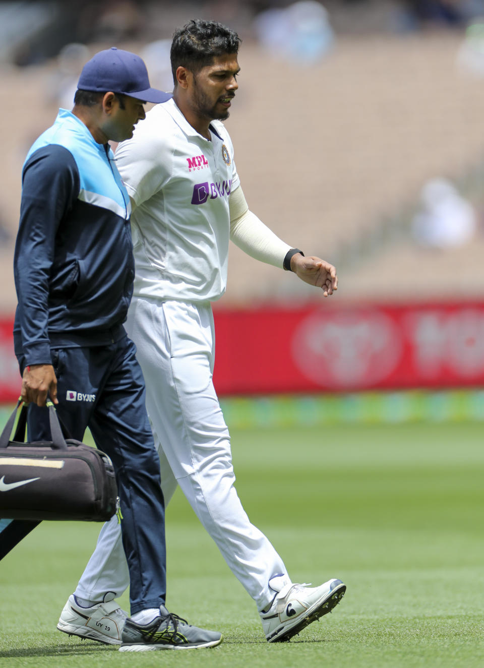 India's Umesh Yadav, right, walks from the field for treatment during play on day three of the second cricket test between India and Australia at the Melbourne Cricket Ground, Melbourne, Australia, Monday, Dec. 28, 2020. (AP Photo/Asanka Brendon Ratnayake)