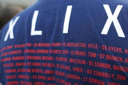 A fan wearing a souvenir t-shirt from Super Bowl XLIX and listing New England Patriots players including quarterback Tom Brady waits in line to hear Brady speak at Salem State University in Salem, Massachusetts, United States May 7, 2015. REUTERS/Brian Snyder - RTX1C136