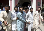 In this May 15, 2019, photo, officials of Pakistan's Federal Investigation Agency escort detain criminals allegedly involved in a trafficking gang to lure Pakistani women into fake marriages, to a court in Faisalabad, Pakistan. (AP Photo/K.M. Chaudary)