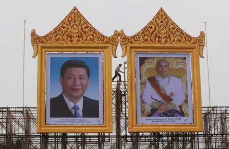 Workers prepare portraits of Chinese President Xi Jinping (L) and Cambodian King Norodom Sihamoni ahead of his visit, in Phnom Penh, October 11, 2016. REUTERS/Samrang Pring