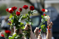 People wave flowers at the farewell hall during the funeral of Alexander Taraikovsky who died amid clashes protesting the election results, in Minsk, Belarus, Saturday, Aug. 15, 2020. Taraikovsky died Monday as demonstrators roiled the streets of the capital Minsk, denouncing official figures showing that authoritarian President Alexander Lukashenko, in power since 1994, had won a sixth term in office. (AP Photo/Sergei Grits)