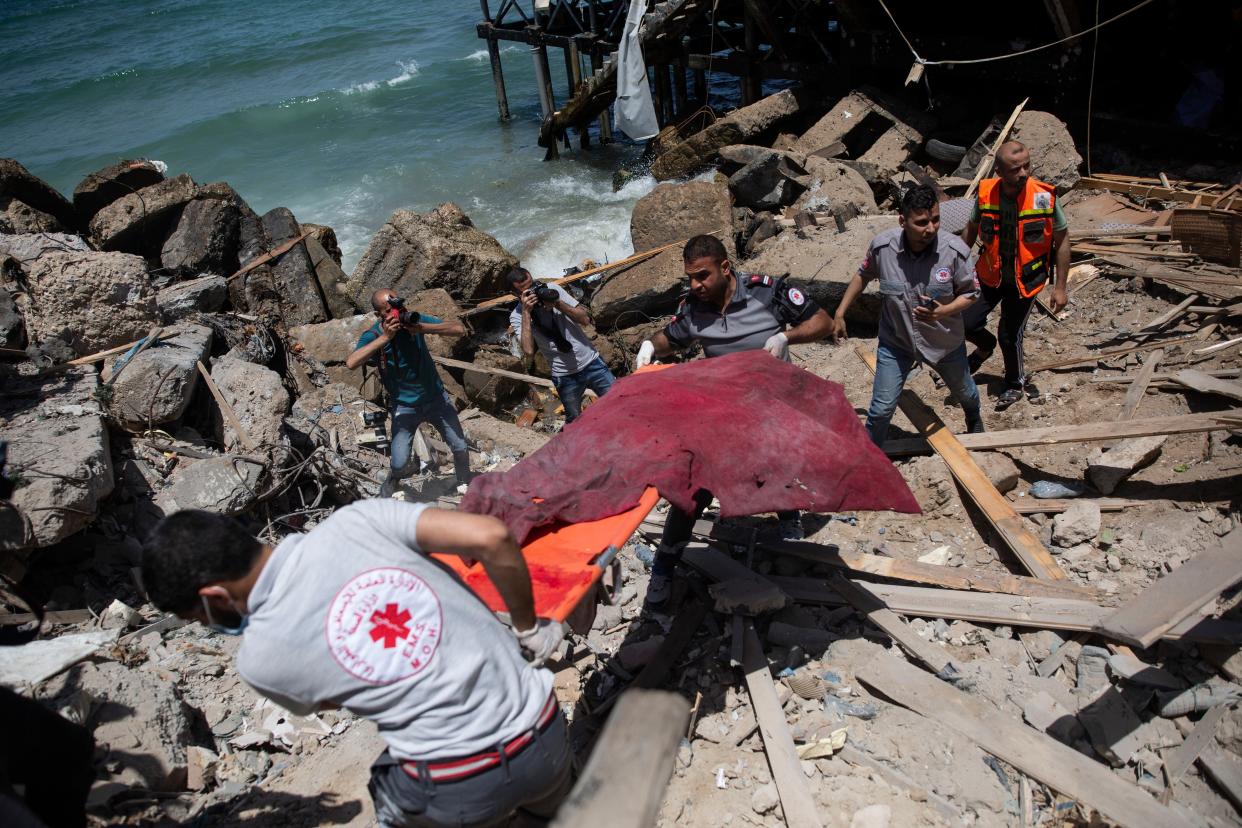 Palestinian rescue workers carry the remains of a man found next to a beachside cafe after it was hit by an Israeli airstrike in Gaza City on Monday, May 17, 2021.